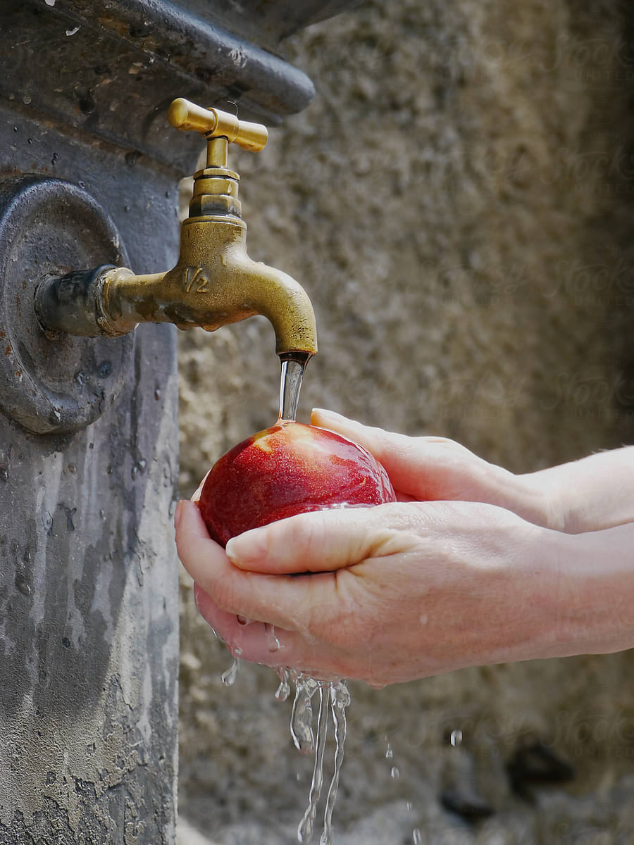 Woman's hands washing apple under running water